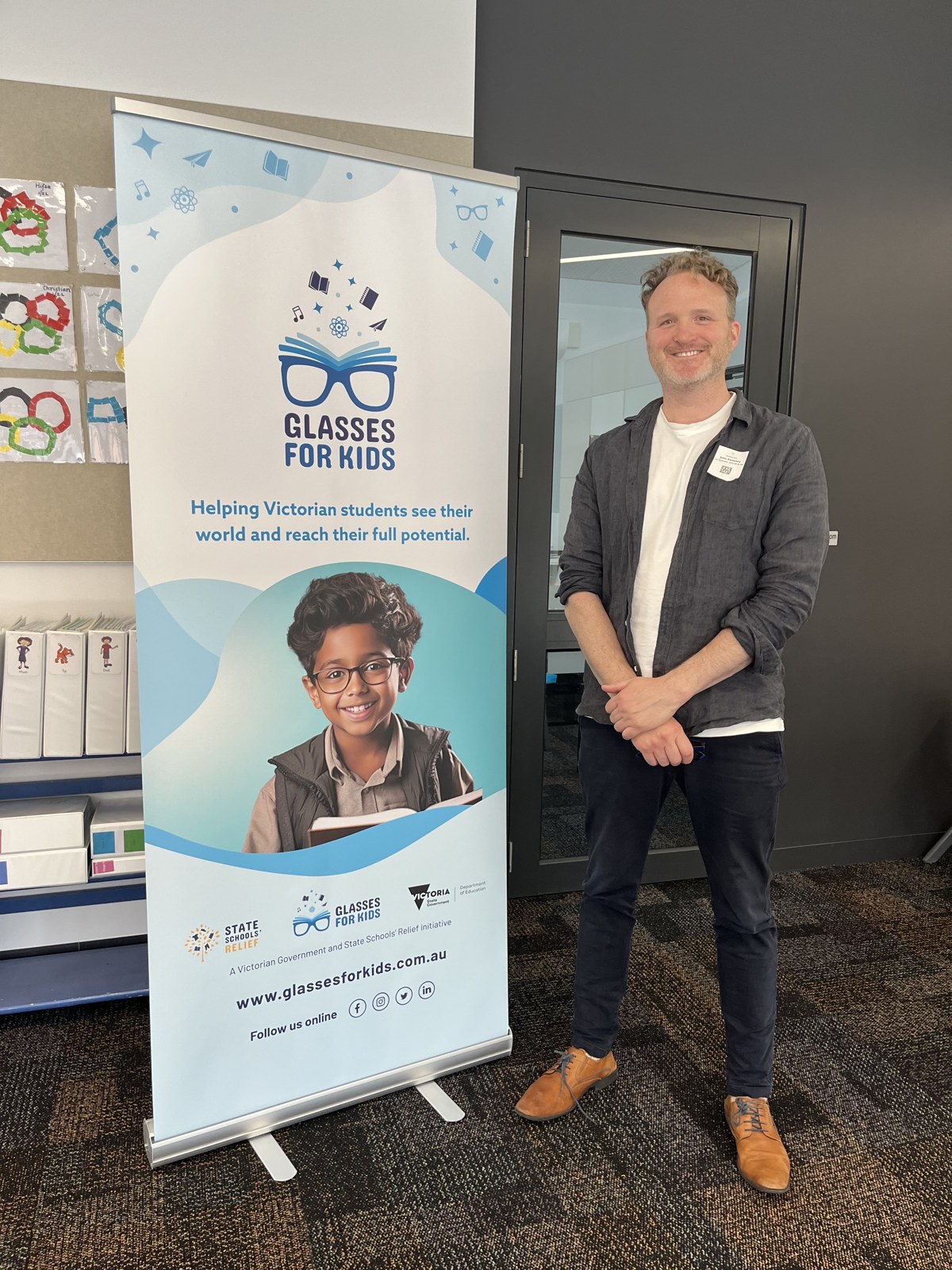 John Sweeney standing beside a Glasses for Kids program banner.